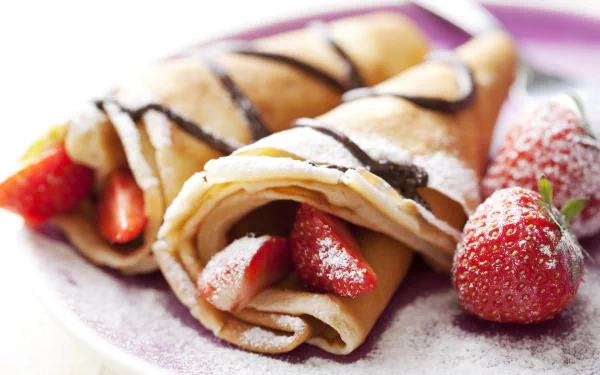 HD desktop wallpaper featuring breakfast crêpes filled with fresh strawberries and drizzled with chocolate, accompanied by whole strawberries on a white plate.
