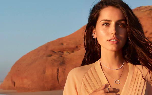 4K Ultra HD wallpaper featuring Cuban actress Ana de Armas with brunette hair, wearing layered jewelry against a red rock desert background.