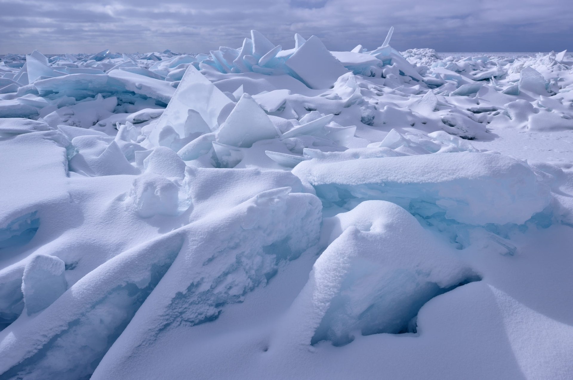 HD PC desktop wallpaper showcasing a winter landscape of snow-covered ice floes under a cloudy sky, capturing the serene and cold beauty of nature.