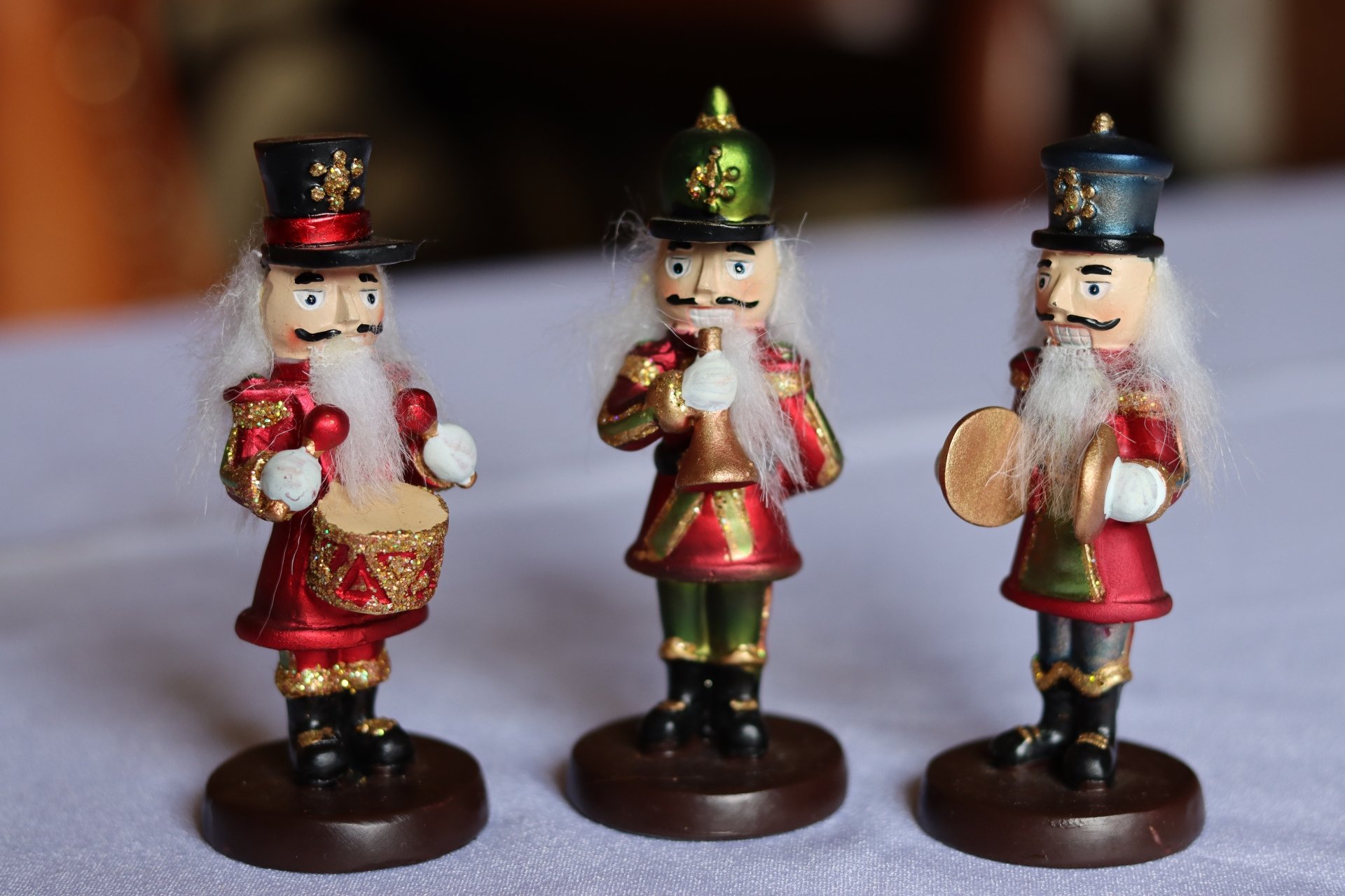 Three Christmas nutcracker figurine ornaments in red and green, one holding a drum and one cymbals, presented as a 4K Ultra HD PC desktop wallpaper background for holiday decor.