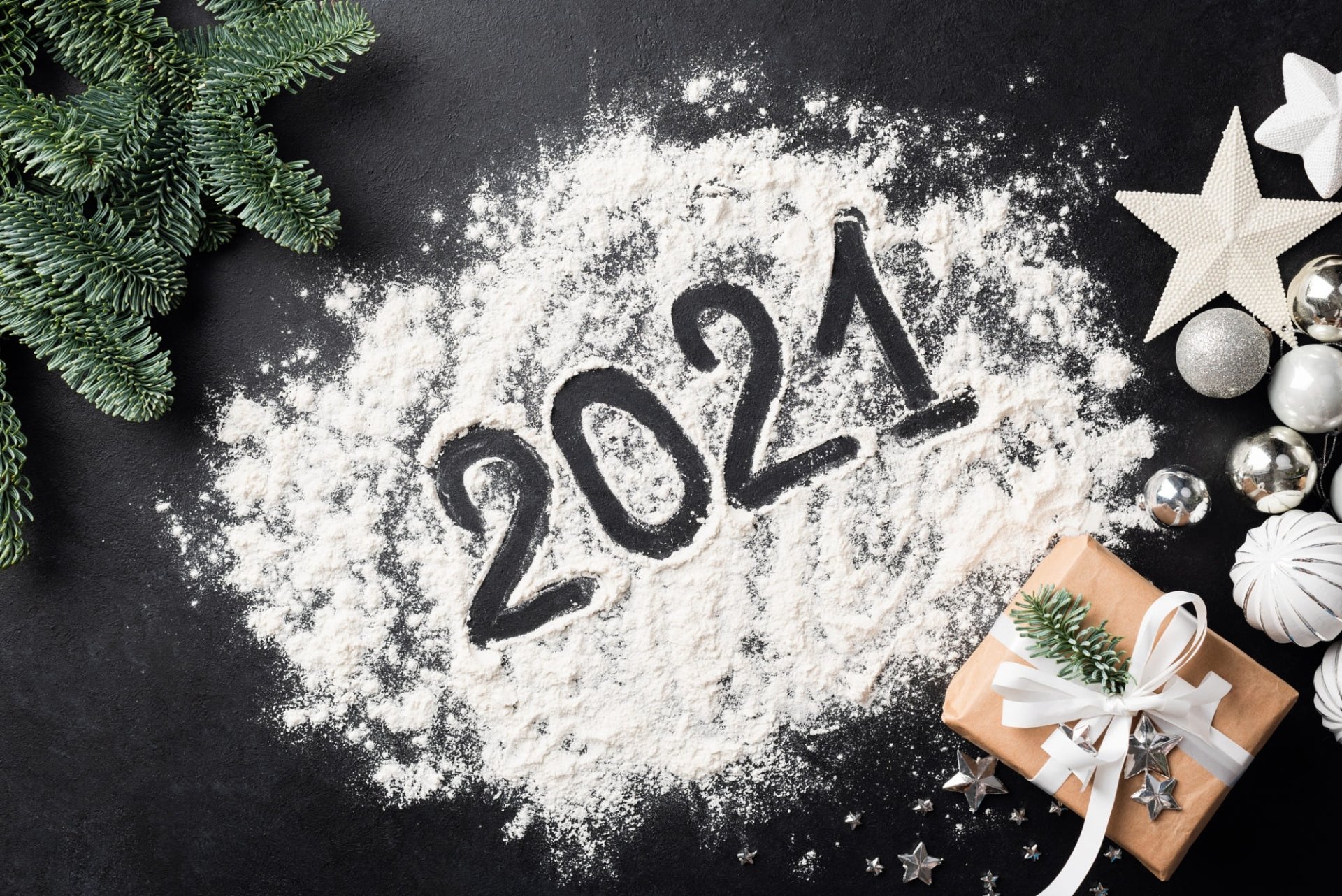 HD PC desktop wallpaper: 2021 written in flour/snow on a black surface, surrounded by fir sprigs, silver baubles, star ornaments and a wrapped gift — holiday New Year 2021.