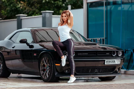 Blonde model poses confidently beside a sleek black Dodge Challenger in this HD Girls & Cars desktop wallpaper and background.