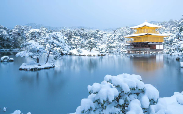 Snow-covered Kinkaku-ji temple in Kyoto, Japan, reflected in a serene lake during winter, showcasing a peaceful religious scene in HD quality.