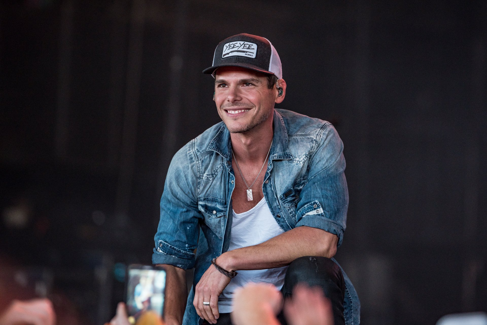 HD desktop wallpaper featuring Granger Smith smiling during a performance, wearing a baseball cap and denim jacket.