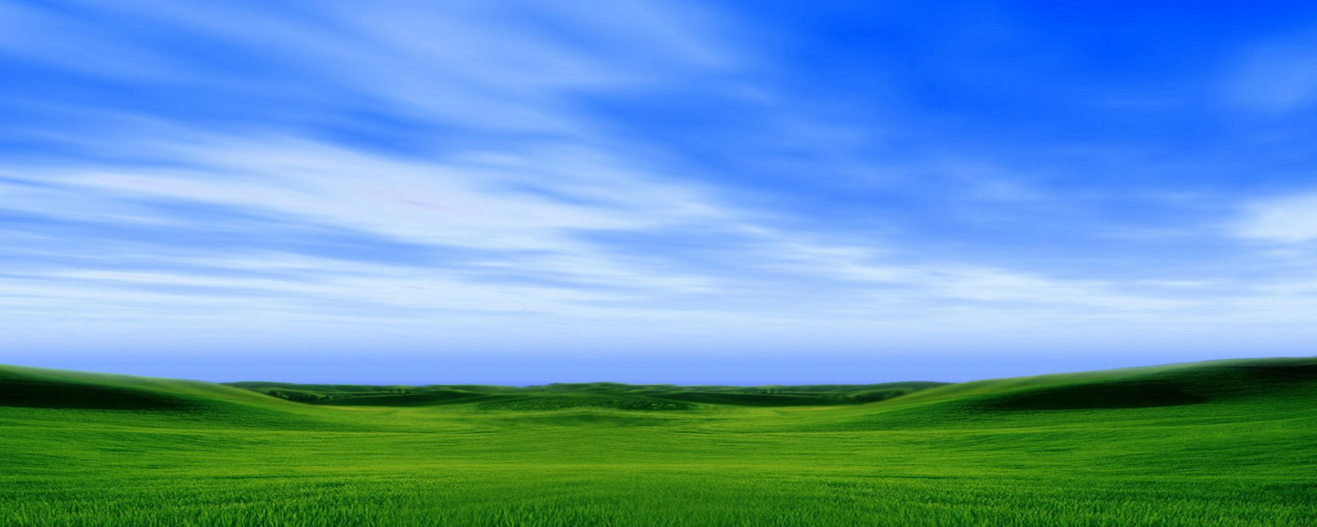 HD PC desktop wallpaper and background showing a wide green rolling meadow under a vivid blue sky with wispy clouds, a serene nature landscape.