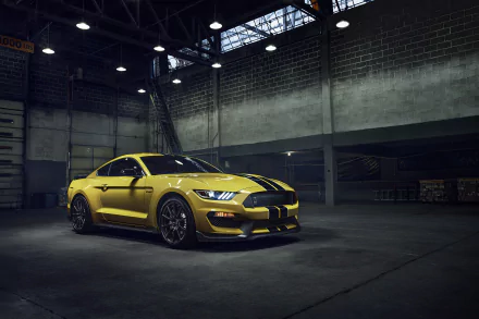 A yellow Ford Mustang GT350 muscle car parked inside a dimly lit industrial garage, captured in 4K Ultra HD for a PC desktop wallpaper.