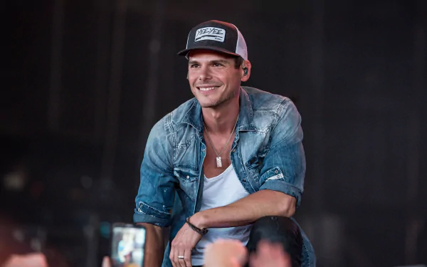 HD desktop wallpaper featuring Granger Smith smiling during a performance, wearing a baseball cap and denim jacket.