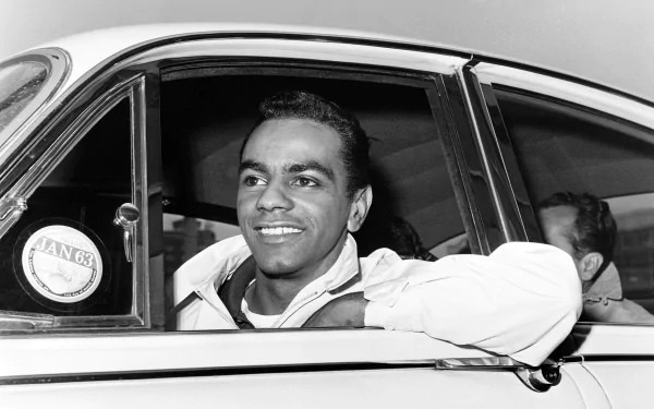 HD desktop wallpaper featuring a black-and-white photo of a smiling man leaning out of a car window.