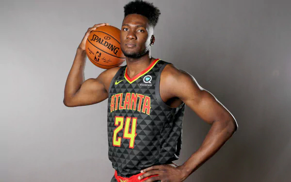 Bruno Fernando poses confidently with a basketball, showcasing his athleticism in an HD desktop wallpaper, representing his time in sports with the Atlanta team.