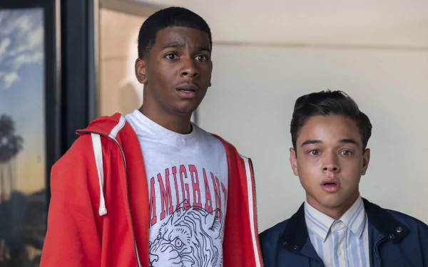 HD desktop wallpaper featuring Brett Gray in a red hoodie alongside a co-star against an indoor backdrop.