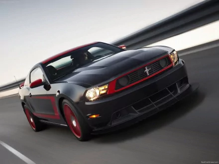 A sleek black Ford Mustang Boss 302 with striking red accents races down a track, showcasing its dynamic design and powerful presence as an HD desktop wallpaper.