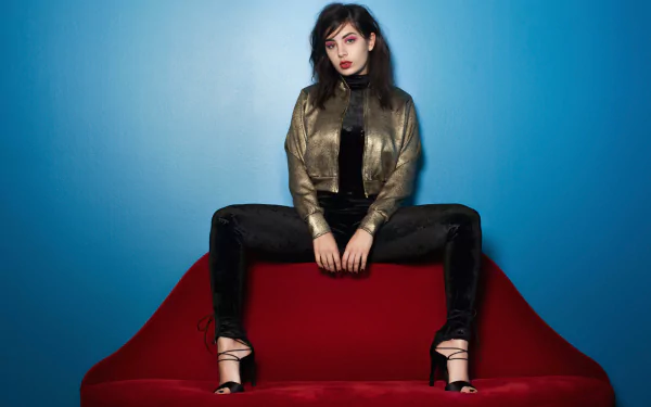 HD desktop wallpaper: pop musician seated on a red sofa against a blue backdrop, wearing a metallic jacket and black pants.