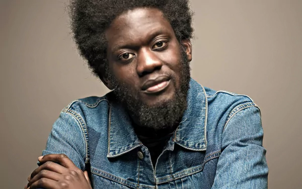 HD desktop wallpaper featuring a portrait of a man in denim, tagged as Michael Kiwanuka, with a neutral background.
