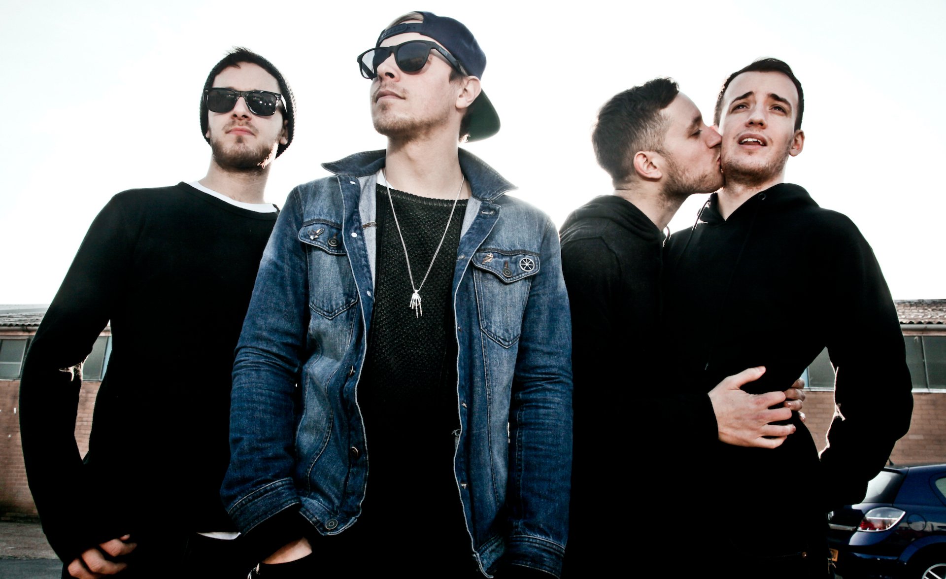 Four trendy individuals posing confidently, making a stylish HD desktop wallpaper for architects with a clear sky backdrop.