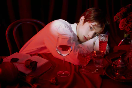 5K Ultra HD PC desktop wallpaper, music (tagged ENHYPEN): moody red-lit portrait of a person leaning on a table with a wine glass and roses.