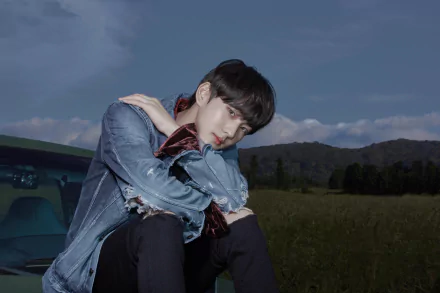 5K Ultra HD PC wallpaper — music-themed, ENHYPEN-inspired image of a young man in a denim jacket leaning on his knees by a car in a grassy field at dusk.