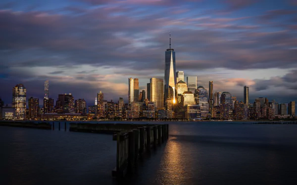 2K Quad HD PC desktop wallpaper: Hoboken, New Jersey, USA view of a city skyline with glass skyscrapers and a towering high-rise at sunset over the Hudson, foreground pier leading into water.