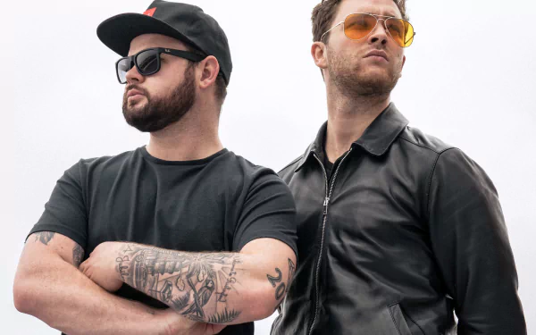 HD wallpaper featuring two confident men associated with Royal Blood, one with tattoos and a cap, the other with sunglasses and a leather jacket, against a clear background.
