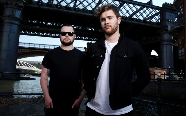 HD wallpaper featuring two members of the band styled for the 'Royal Blood' theme, posing confidently in front of an urban bridge.