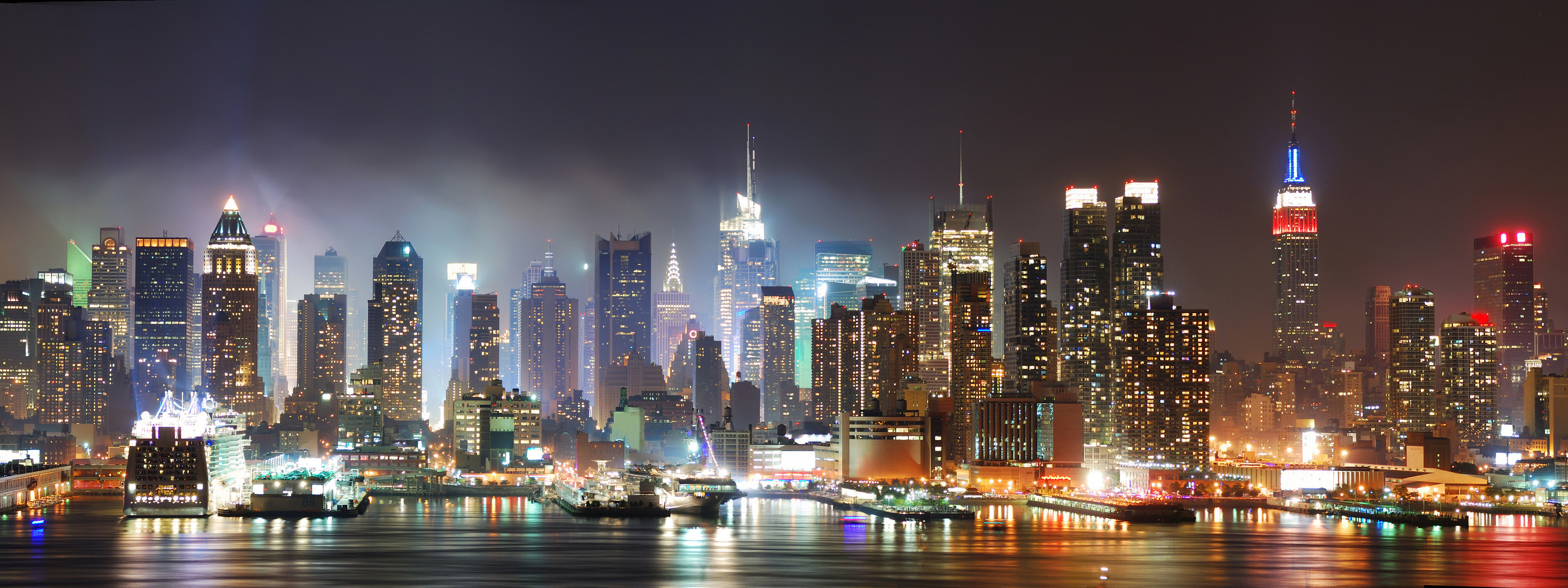 Manhattan skyline at night, featuring iconic buildings in New York City like the Empire State Building.
