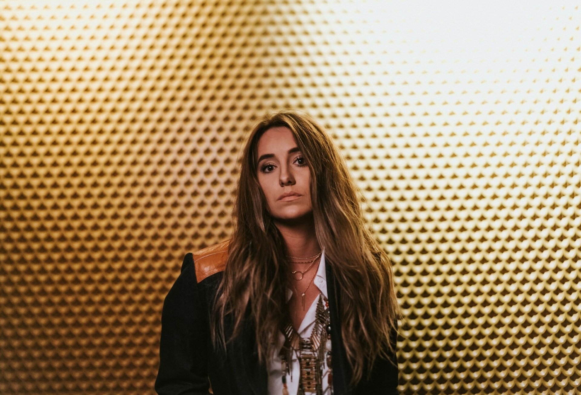 HD desktop wallpaper of a woman standing against a textured golden background, providing a stylish and bold backdrop.