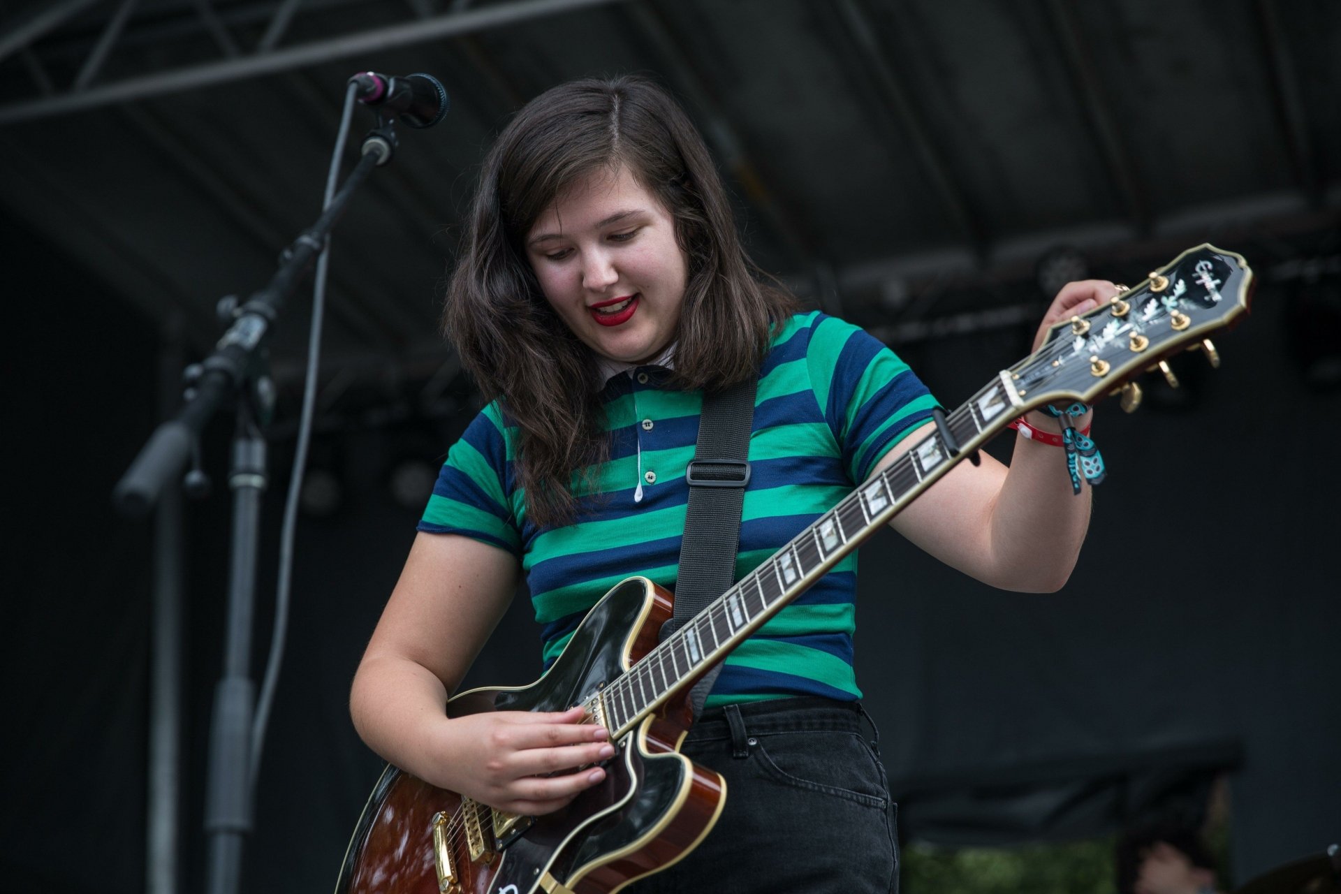 Musician in a striped shirt playing electric guitar on stage, suitable as an HD desktop wallpaper and background.