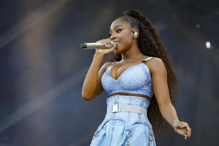 A vibrant HD desktop wallpaper featuring Normani performing on stage, captured mid-song, showcasing her dynamic presence and style in the music scene.