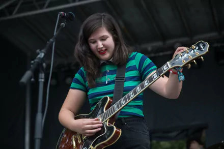 Musician in a striped shirt playing electric guitar on stage, suitable as an HD desktop wallpaper and background.