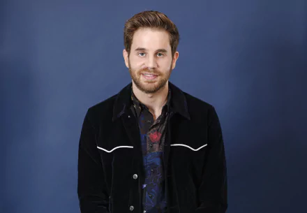 Smiling man in a black jacket with white trim on a blue background, HD desktop wallpaper.