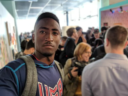 A high-definition desktop wallpaper featuring celebrity Marques Brownlee taking a selfie amidst a crowd, capturing a vibrant and engaging atmosphere.