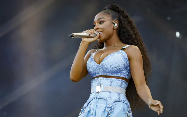 A vibrant HD desktop wallpaper featuring Normani performing on stage, captured mid-song, showcasing her dynamic presence and style in the music scene.