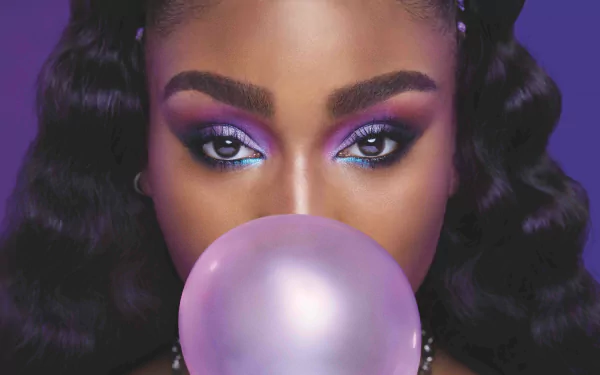 HD desktop wallpaper featuring a close-up of a woman with vibrant purple makeup blowing a bubble gum bubble, with a stylized purple backdrop.