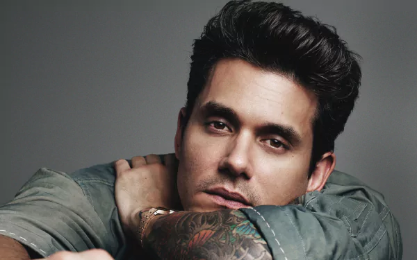 HD desktop wallpaper featuring a portrait of a man with tattoos, posing with a thoughtful expression.