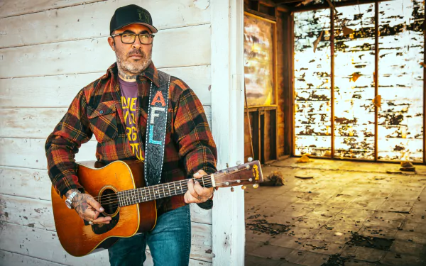Aaron Lewis playing guitar in a rustic setting, a vibrant HD desktop wallpaper.