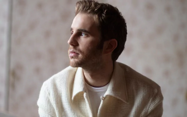 HD desktop wallpaper featuring a contemplative individual in a light-colored jacket, set against a soft, textured background.