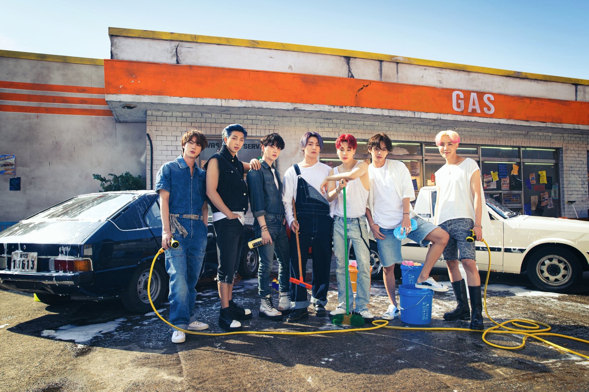 BTS members RM, Suga, Jin, J-Hope, Jimin, V, and Jungkook pose together in front of a gas station, captured in a 4K Ultra HD K-pop music desktop wallpaper.