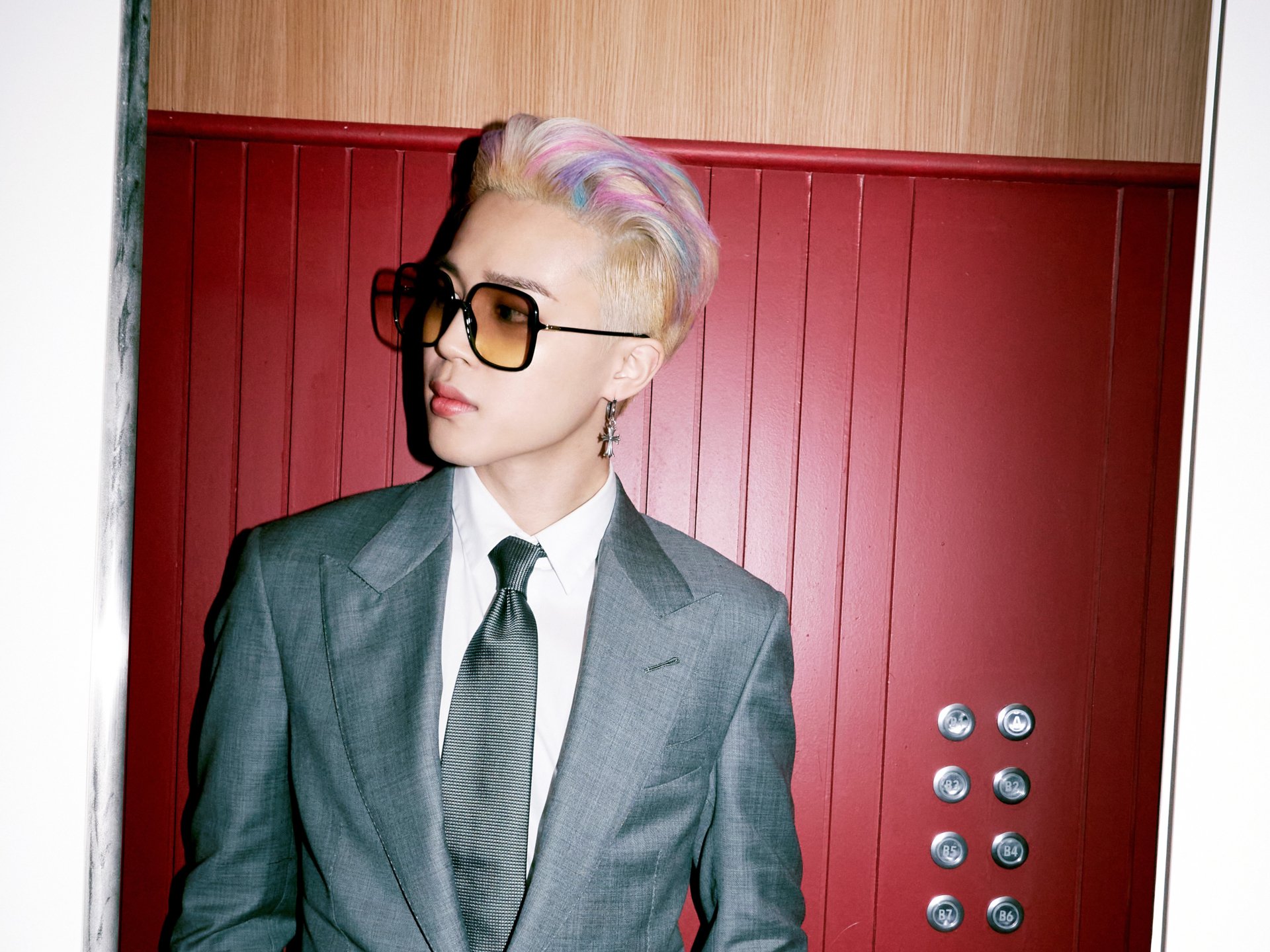 Jimin from BTS in a gray suit and tie with pastel-colored hair and sunglasses, featured in a 4K Ultra HD K-pop music desktop wallpaper background.