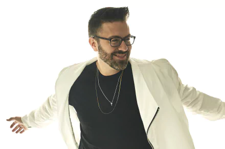 Stylish man in glasses posing with white blazer over black shirt for a HD desktop wallpaper background.