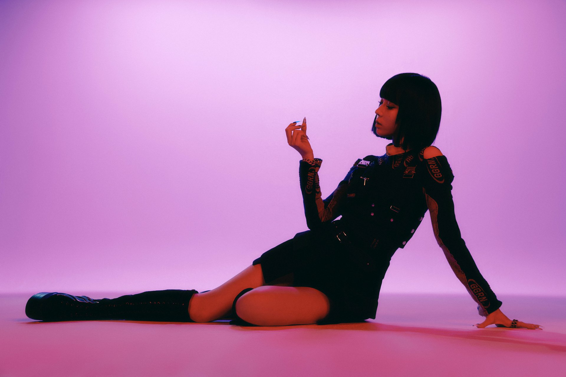 Seated female singer with a bob haircut in a black outfit on a purple-lit floor, music-themed 2K Quad HD PC desktop wallpaper background.