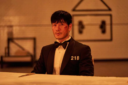 HD PC desktop wallpaper featuring Cho Sang-Woo from the TV show Squid Game, dressed in a black tuxedo with the number 218.
