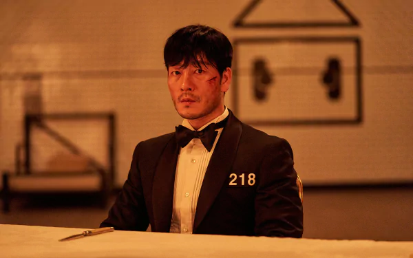 HD PC desktop wallpaper featuring Cho Sang-Woo from the TV show Squid Game, dressed in a black tuxedo with the number 218.