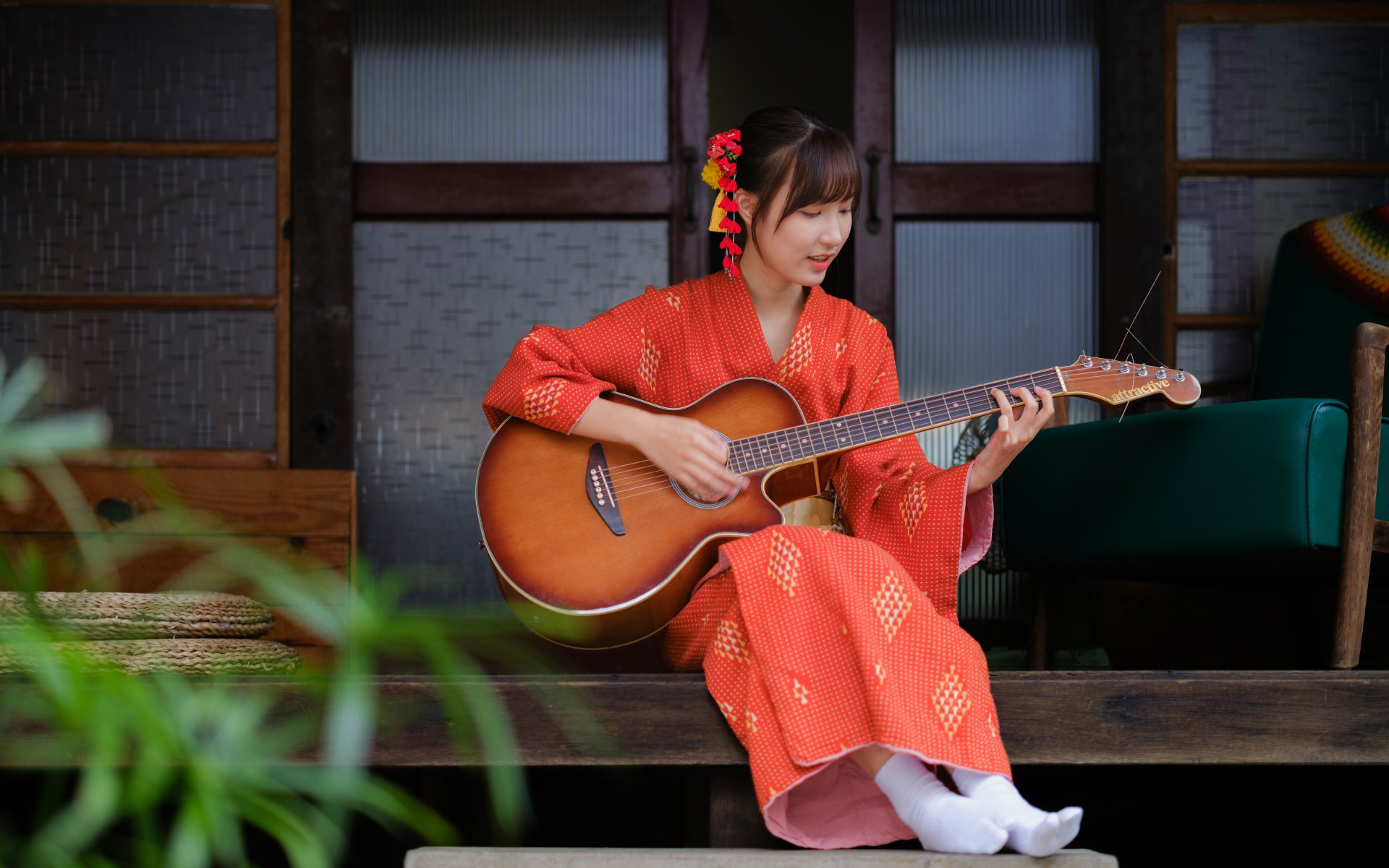 A woman in a vibrant kimono plays an acoustic guitar, seated on a wooden porch with traditional sliding doors in the background, captured in 4K Ultra HD detail.