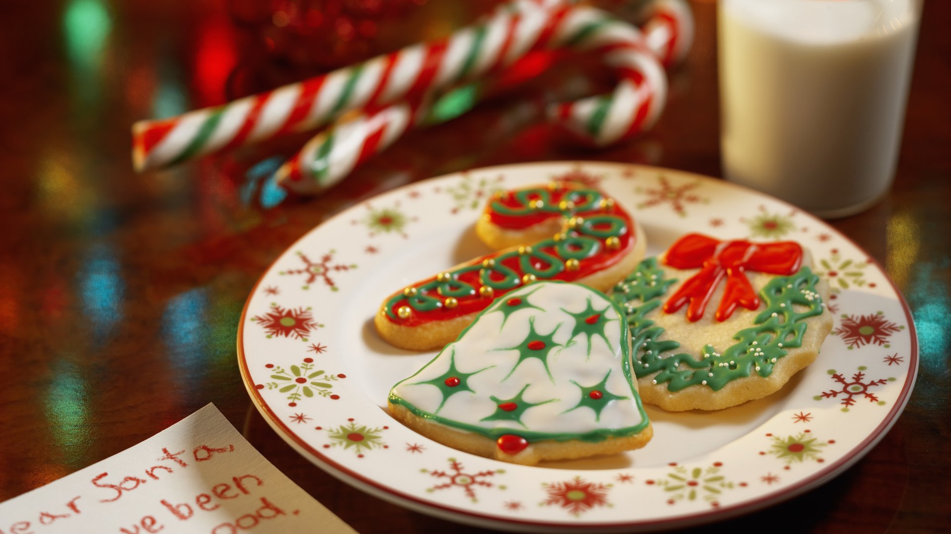 4K Ultra HD desktop wallpaper featuring a festive plate of decorated Christmas cookies with candy canes and a glass of milk in a warm, holiday setting.