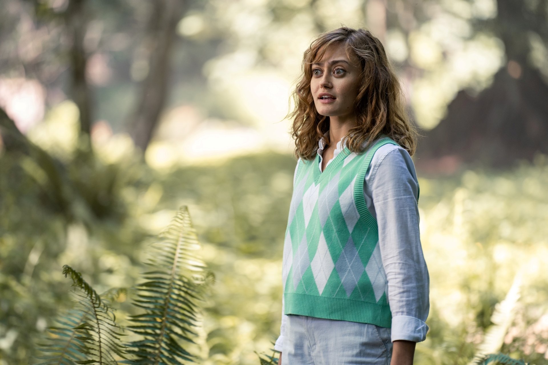 Sunlit forest portrait of a woman in a green argyle vest, Yellowjackets TV show 4K PC desktop wallpaper.
