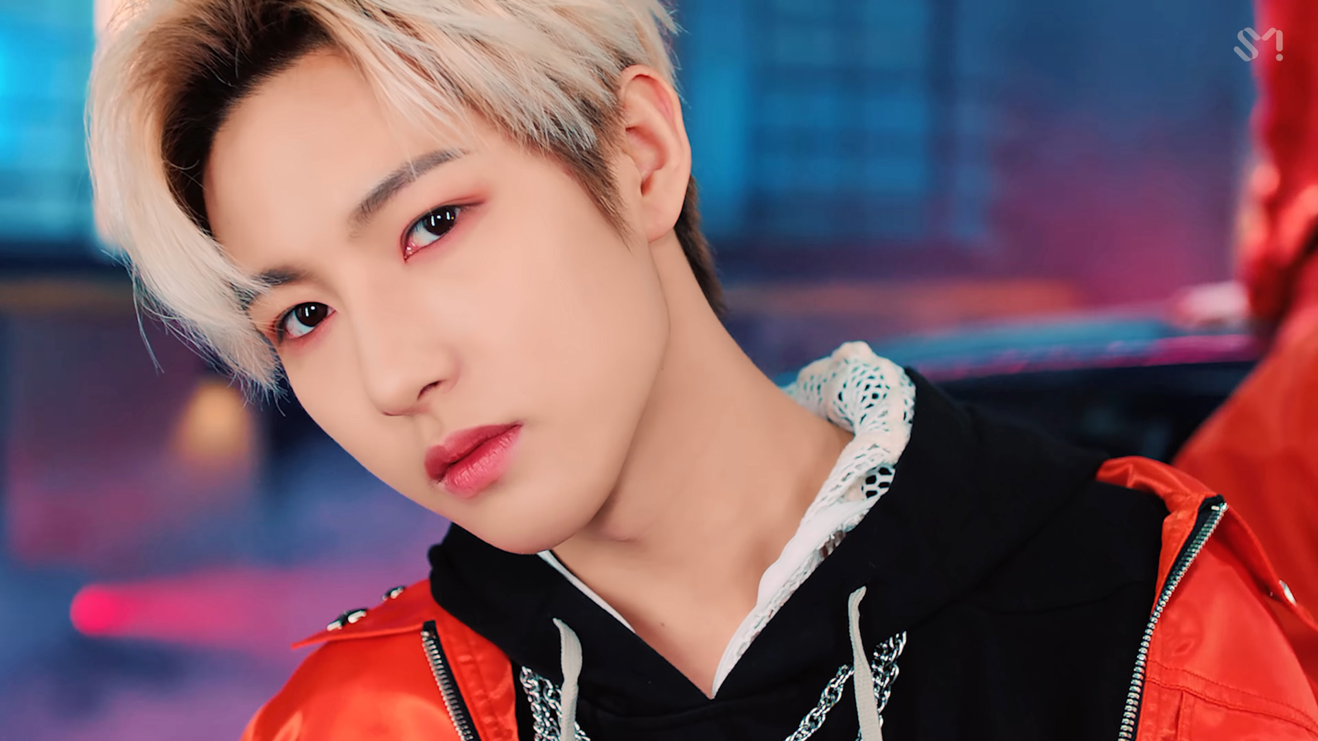 HD PC wallpaper — close-up of a blond-haired K-pop performer in a red jacket against neon blue-pink lights; music-themed NCT desktop background.