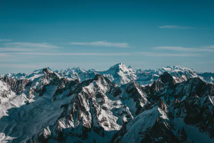 Snow-covered mountain peaks stretch beneath a clear blue sky in this stunning 8K Ultra HD nature desktop wallpaper.
