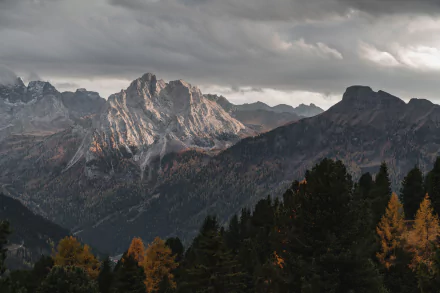 4K Ultra HD desktop wallpaper showcasing the rugged Dolomites in the Alps under moody skies, with autumnal trees in the foreground.