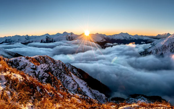 5K Ultra HD PC desktop wallpaper: sunrise over snow‑capped mountains rising above a vast sea of clouds, a serene nature mountain panorama.