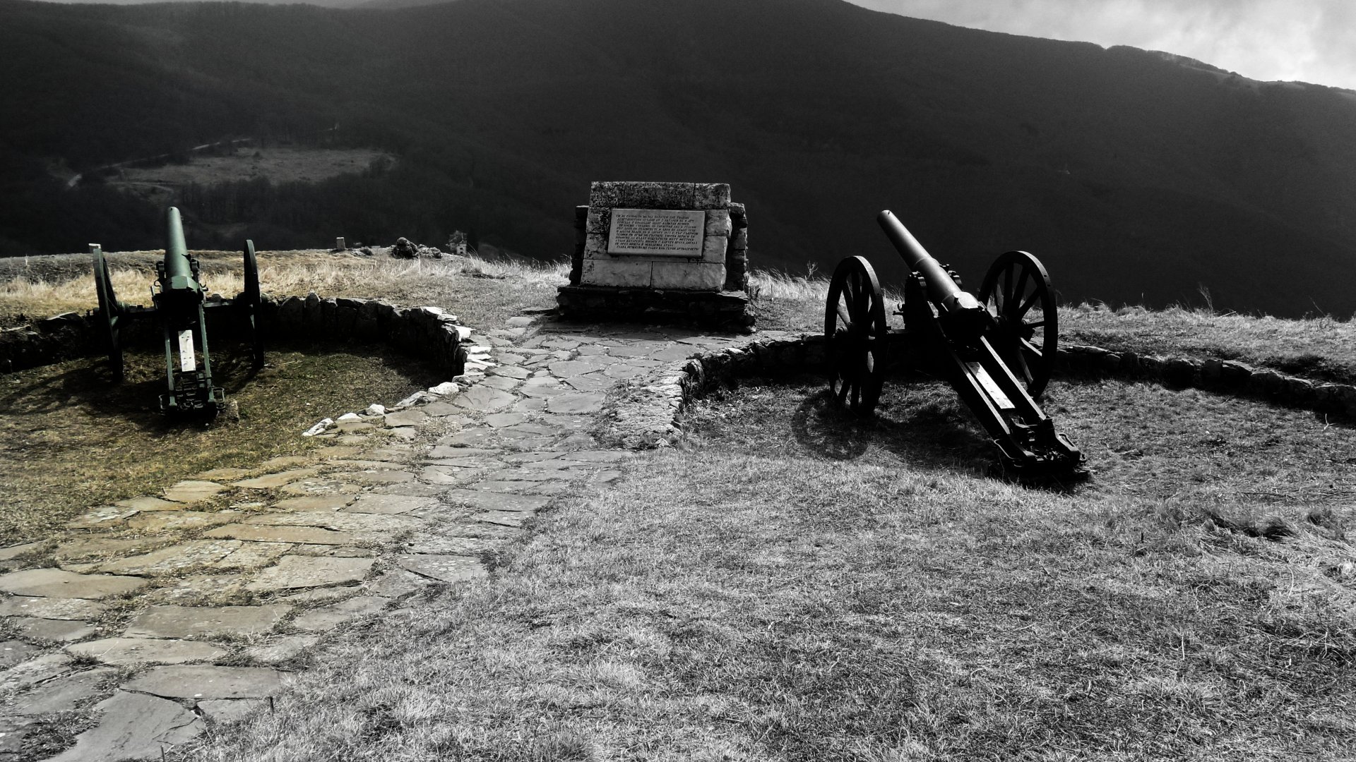 4K Ultra HD desktop wallpaper featuring historical military artillery positioned on a stone-paved hill with dramatic mountainous landscape in the background.