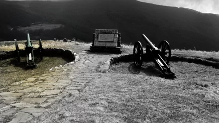 4K Ultra HD desktop wallpaper featuring historical military artillery positioned on a stone-paved hill with dramatic mountainous landscape in the background.